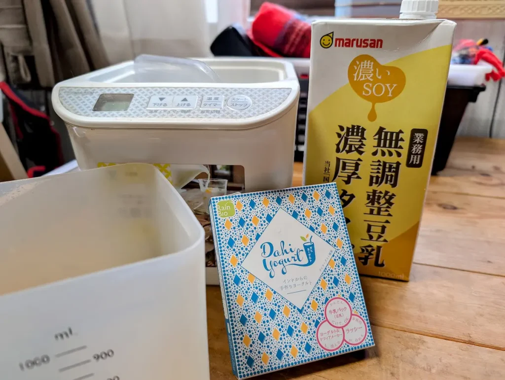 豆乳ヨーグルトメーカー、マルサン濃いSOY無調整豆乳、Dahiヨーグルト種菌、水切りコンテナを並べた、ソイクリームチーズ作りの道具と材料