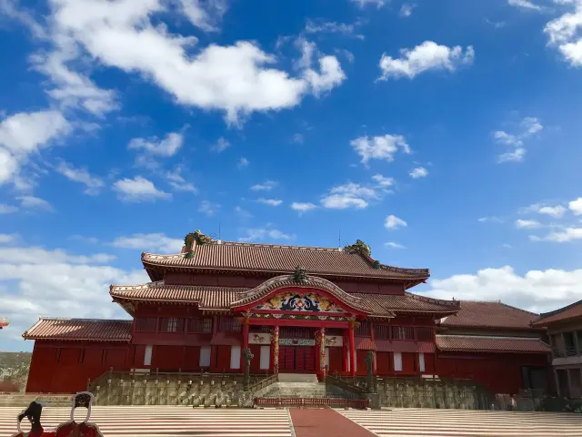 青空を背景にした首里城正殿。朱色の建物と赤瓦の屋根が特徴の琉球王国の王宮